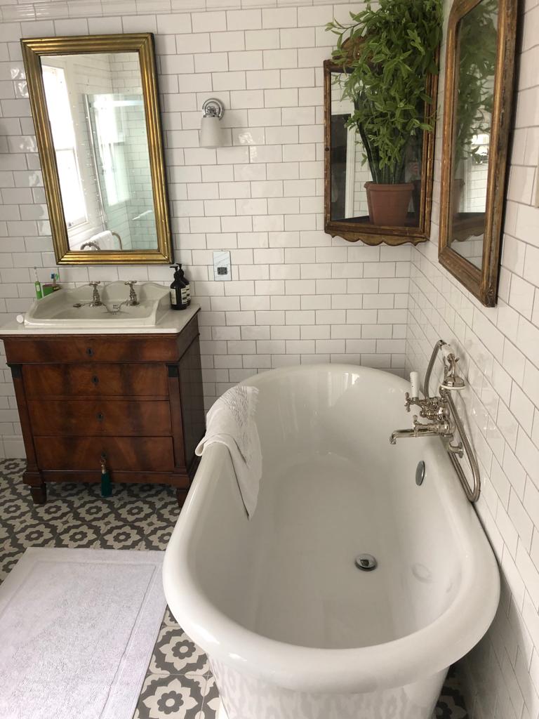 A finished bathroom — freestanding bath, traditional brassware and patterned tiling.