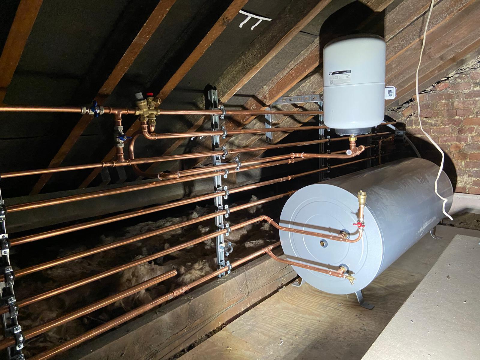 Loft pipework and hot-water cylinder — clean, supported copper runs.